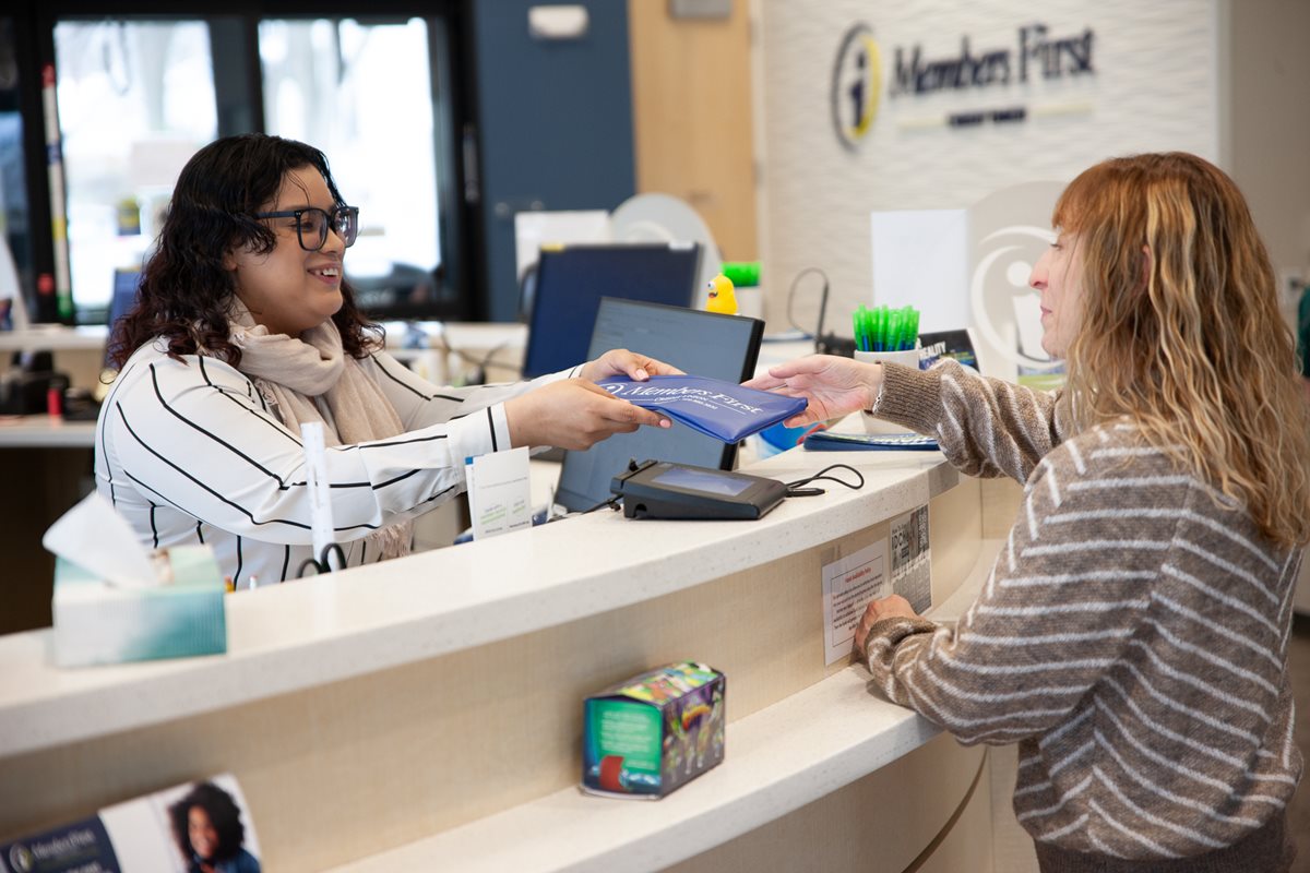 Financial Services Associate Hands Money Pouch to MFCU Member